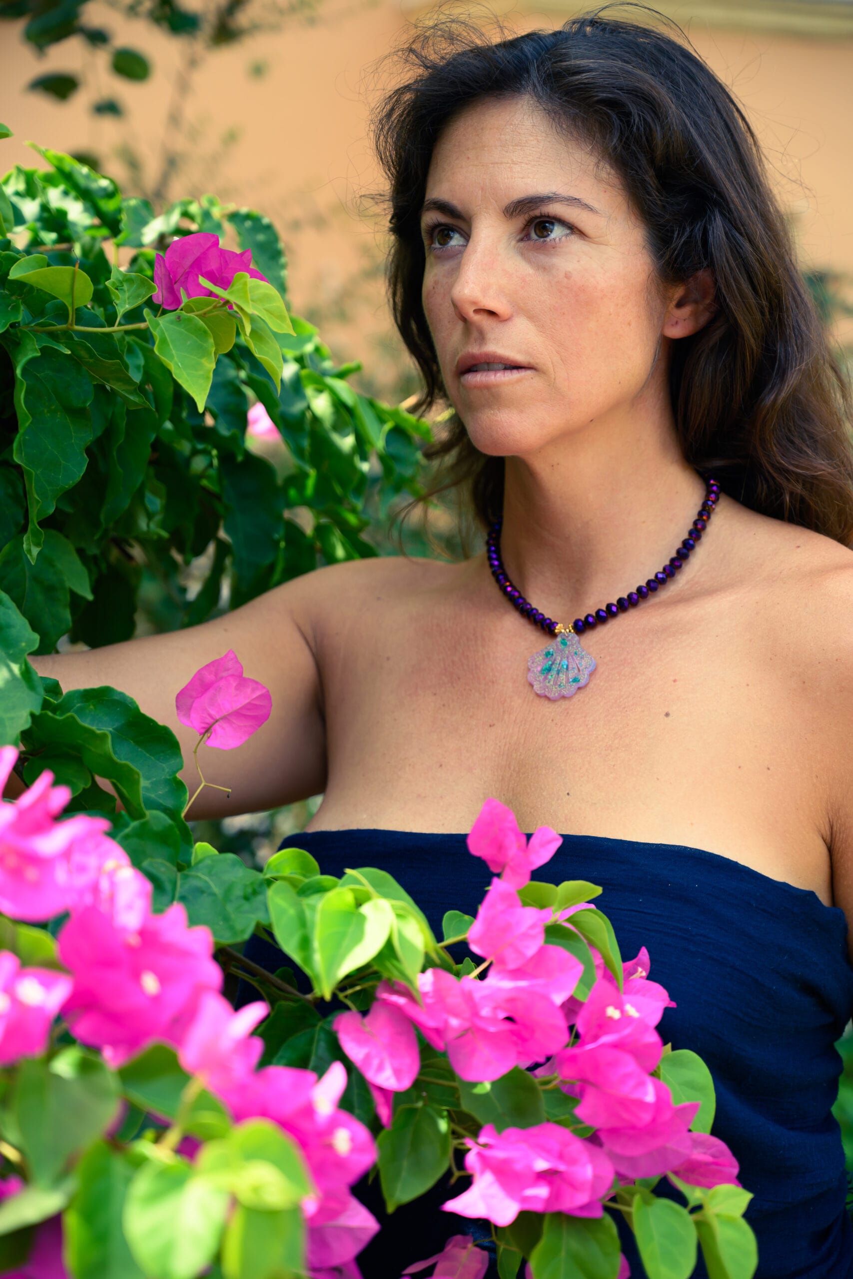 Collar de cuentas moradas facetadas con colgante de concha puesto en el cuello