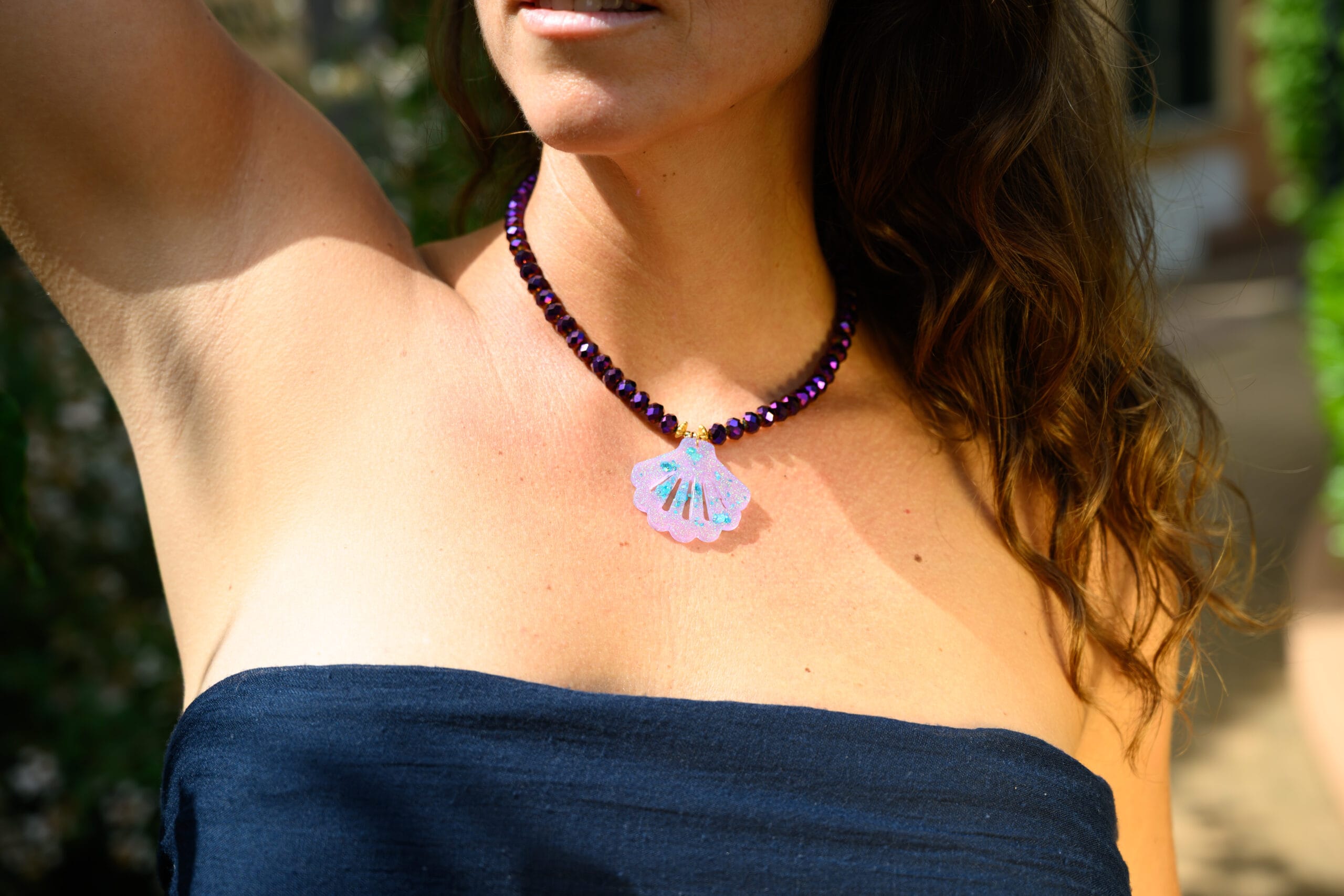 Cuentas moradas con brillo metalizado del collar Concha Sirena detalle desde frente, modelo luciendo en su cuello luz mediterranea