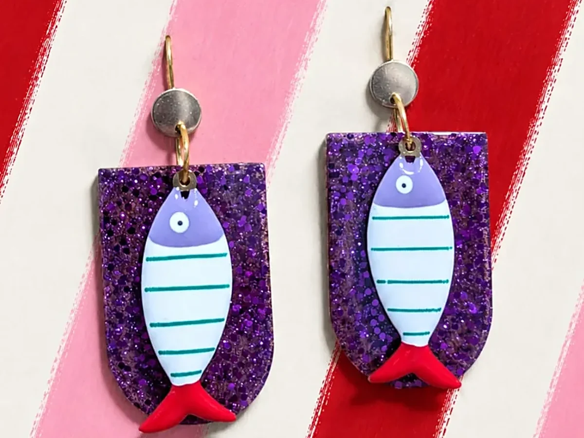 Pendientes Cala Sardinera de resina con sardina esmaltada sobre placa morada con glitter, hechos a mano en Xàbia