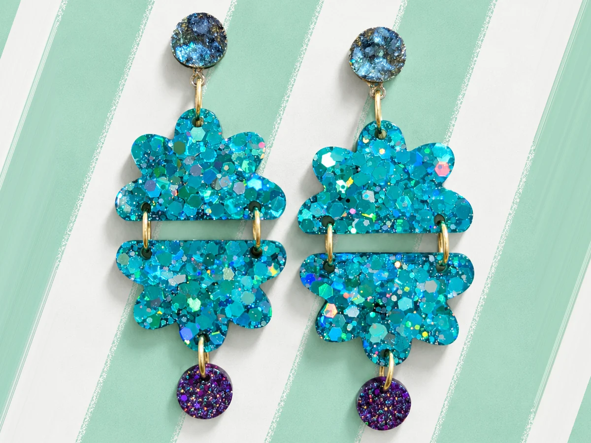 Pendientes Flor de Caleta con flor turquesa de glitter holográfico partida en dos y gota morada, hechos a mano en Xàbia